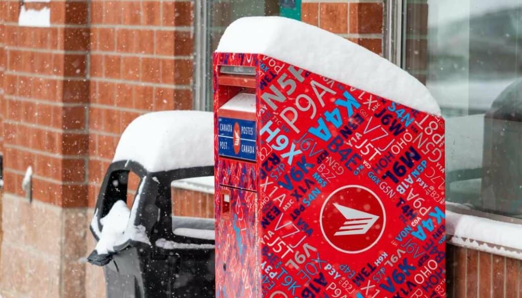 Canada post mailbox besides dustbin with heavy snow