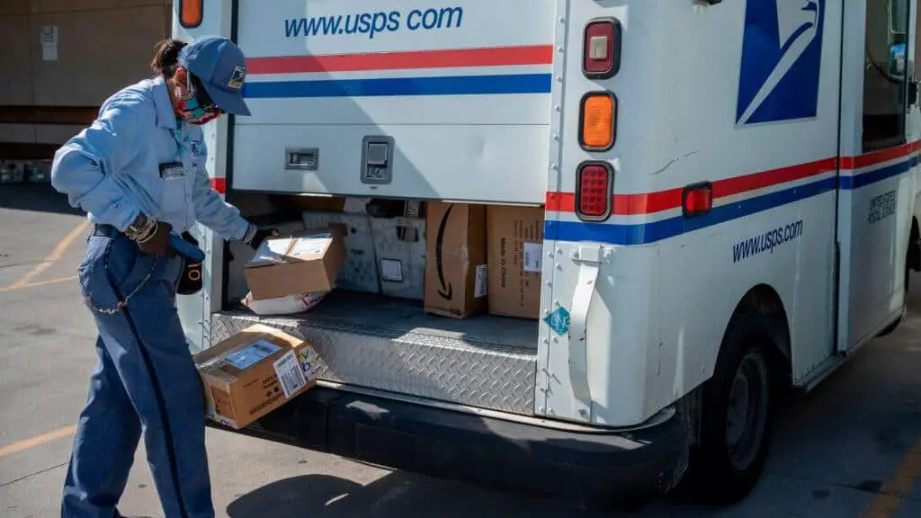 The girl is scanning the USPS packages from a truck.