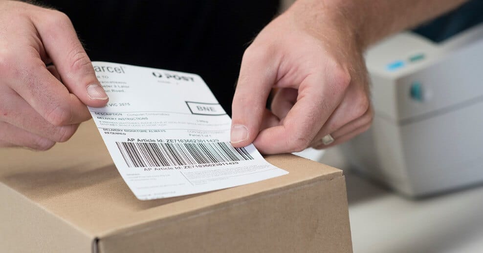 A man is attaching a return label on the shipping box