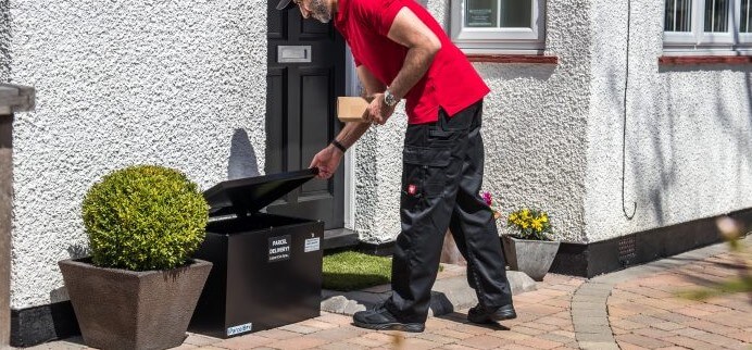 A man is keeping box at metal box outside home